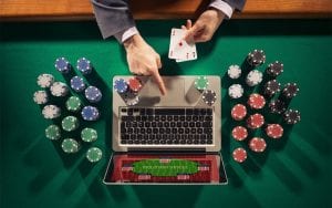 a man holding cards and poker chips in front of laptop online casinos 