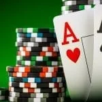 poker chips and two aces standing in front of a green background