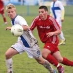 two men playing football on a green field